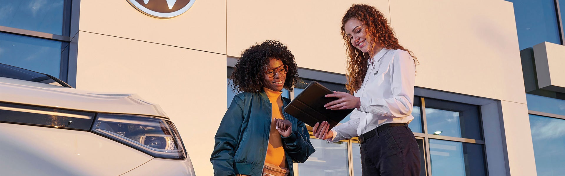 Dealership employee showing a person a vehicle outside the dealership