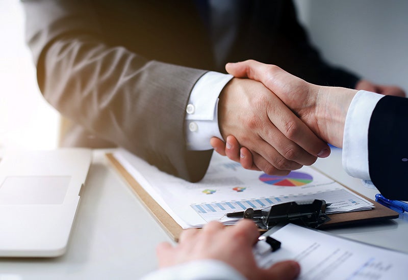Salesperson and customer shake hands over financial documents